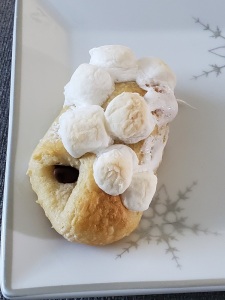 1 s'mores roll-up on white plate with toasted marshmallows on top